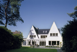 Gartenfassade mit markanten Spitzgiebeln, großzügiger Terrasse und anschließender Rasenfläche