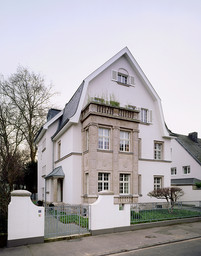 Straßenfassade der denkmalgeschützten Stadtvilla mit historischem Natursteinerker und Mansarddach