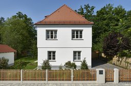 Symmetrische Straßenfassade des zweigeschossigen Einfamilienhauses mit Walmdach und Sprossenfenstern