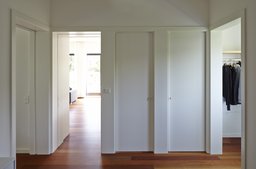 Flurbereich mit wandbündigen weißen Türen, Holzparkett und Blickachsen