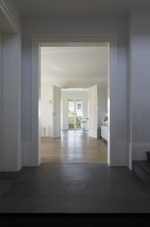 Blickachse vom Naturstein-Entree durch Flügeltüren in den hellen Wohnbereich