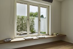 Tiefe hölzerne Fenstersitzbank mit Blick in den geschützten Außenbereich