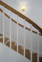 Detailansicht der Holztreppe mit weißem Geländer und aufliegendem Holzhandlauf