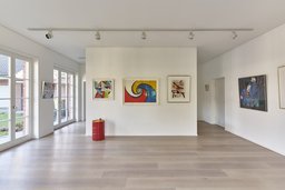 Lichtdurchfluteter Atelierraum mit hellem Dielenboden, Kunstwerken und bodentiefen Fenstern