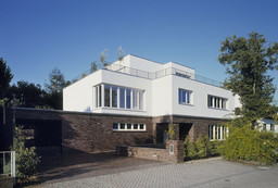 Straßenansicht des kubischen Einfamilienhauses mit Klinkersockel und weißem Obergeschoss