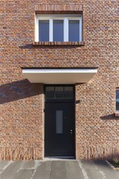 Hauseingang mit auskragendem Betonvordach in rotbunter Klinkerfassade