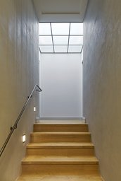 Treppenaufgang mit Eichenstufen, integrierter Wandbeleuchtung und gerasterter Lichtdecke