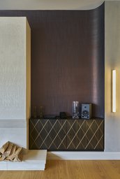 Kaminbereich mit maßgefertigtem Rauten-Sideboard und gerundeter dunkler Wandverkleidung