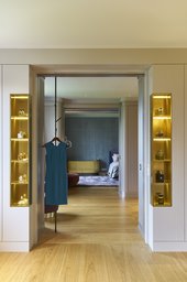 Ankleide mit beleuchteten Messingvitrinen und Blickachse in das Schlafzimmer