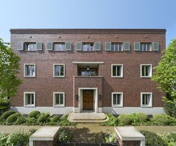 Symmetrische Hauptfassade mit Natursteinportal, zentraler Loggia und hellem Natursteinsockel