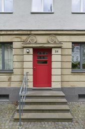 Detailansicht des Hauseingangs mit Werksteinportal, Freitreppe und roter Holztür
