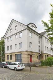 Eckansicht des sanierten Mehrfamilienhauses mit Werksteinsockel und Giebelfassade
