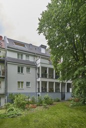 Sanierte Hoffassade mit mehrgeschossiger Balkonanlage zum begrünten Garten