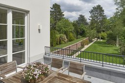 Terrasse mit filigranem Geländer und Ausblick in den weitläufigen Garten