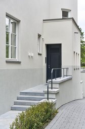 Hauseingang mit steinerner Außentreppe, filigranem Geländer und dunkelblauer Eingangstür