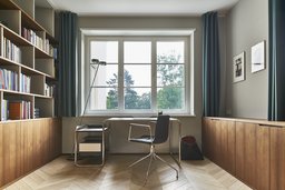 Arbeitszimmer mit maßgefertigten Holzeinbauten, Schreibtisch vor Fenster und Fischgrätparkett
