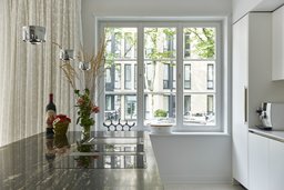 Küche mit dunkler Naturstein-Arbeitsplatte und Ausblick durch dreiteiliges Sprossenfenster