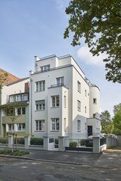Perspektivische Straßenansicht des Gebäudes mit Erker, abgerundetem Treppenturm und Einfahrt