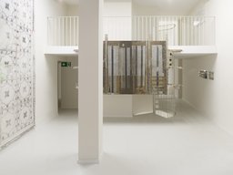 Zweigeschossiger Ausstellungsraum mit Empore, weißer Stütze und Spindeltreppe
