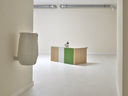 Minimalistischer Ausstellungsraum mit farbigem Objekt und sichtbarem Lüftungsrohr