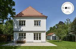 Ansicht der Gartenfassade mit Steinterrasse, Sprossenfenstern und klassischem Walmdach
