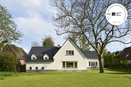 Gartenansicht des Landhauses mit weißer Putzfassade, Satteldach, Gauben und Walnussbaum