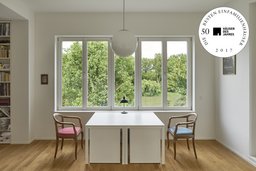 Studio mit weißem Tisch, Kugelleuchte und Fensterfront zum Rhein