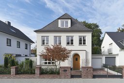 Straßenfassade mit Walmdach, Dachgaube, Rundbogeneingang und Klinkereinfriedung