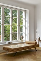 Wohnzimmer mit vierteiligem Sprossenfenster, Fischgrätparkett und lederner Tagesliege