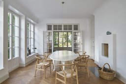 Lichtdurchflutetes Esszimmer mit Fischgrätparkett, weißem Kamin und verglaster Flügeltür