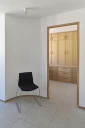 Geschwungene Wand mit Warteplatz und Durchgang zu maßgefertigten Einbauschränken
