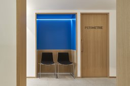 Blaue Wartenische mit indirekter Beleuchtung neben der Perimetrie-Praxistür