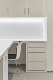 Weißer Praxisarbeitsplatz mit maßgefertigten Einbaumöbeln und integrierter Lichtleiste