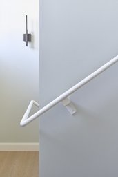 Treppendetail mit weißem Stahlhandlauf und minimalistischer Wandleuchte