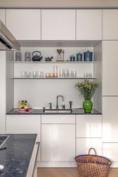 Minimalistische weiße Küchenzeile mit integrierter Spülnische und dunkler Naturstein-Arbeitsplatte