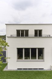 Gartenfassade mit breitem Erdgeschossfenster, zurückspringender Dachterrasse und filigranem Geländer