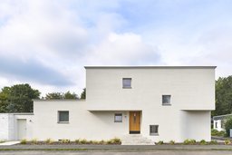 Straßenfassade des kubischen Einfamilienhauses mit Besenstrichputz und überdachtem Hauseingang
