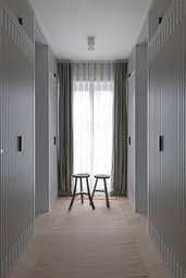 Ankleide mit raumhohen Einbauschränken in Lamellenoptik und bodentiefem Fenster