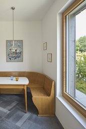 Essplatz mit hölzerner Eckbank, Natursteinboden und großem Holzfenster