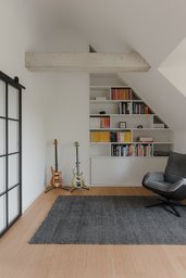 Maßgefertigtes weißes Bücherregal unter der Dachschräge mit freiliegendem Betonunterzug