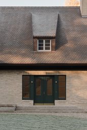 Eingang mit zweiflügeliger dunkelgrüner Haustür in heller Klinkerfassade und Schleppgaube