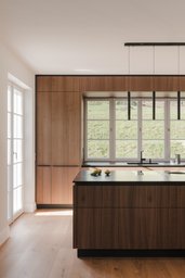 Moderne Holzküche mit Kücheninsel, Einbauschränken und breitem Fenster ins Grüne