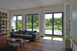 Lichtdurchfluteter Wohnraum mit Holzdielenboden und bodentiefen Fenstertüren zum Garten