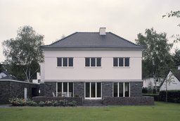 Symmetrische Gartenfassade mit gemauerter Klinkerterrasse, bodentiefen Fenstern und Walmdach