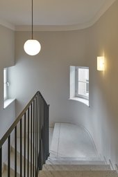 Treppenhaus mit gerundeter Wand, hellem Terrazzoboden und filigranem stahlgeländer