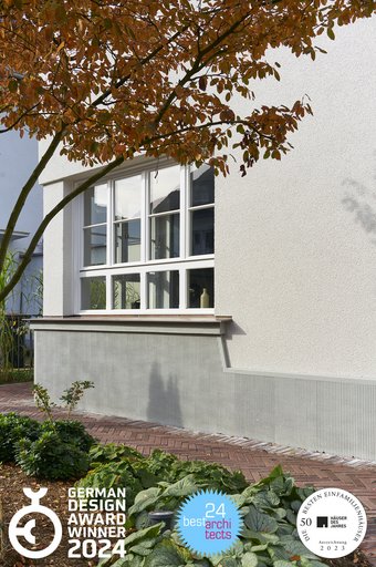 Fassadendetail Sockel mit Kammstruktur, weißem Sprossenfenster und Klinkerpflaster im Vorgarten